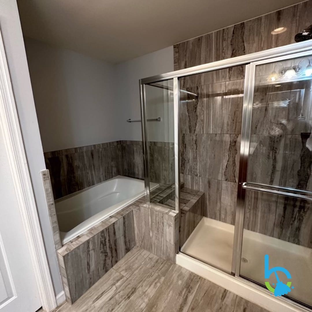 Clean bathroom with a soaking tub, wood-look tile and a glass shower