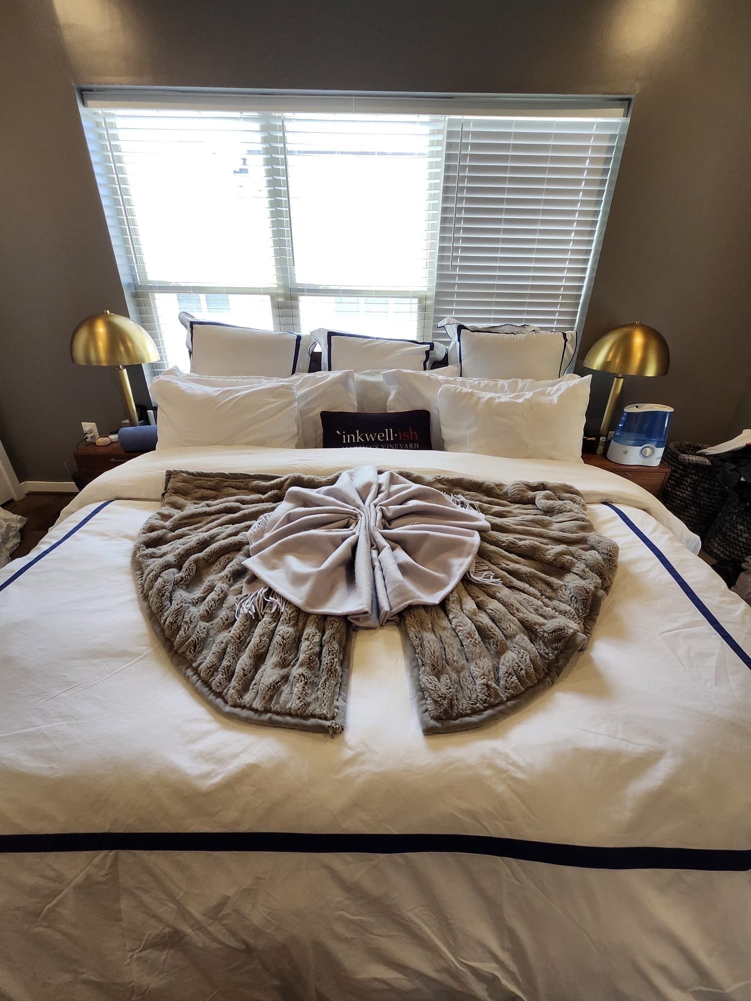 Bed with white linens, gold bedside lamps and a throw folded into a bow