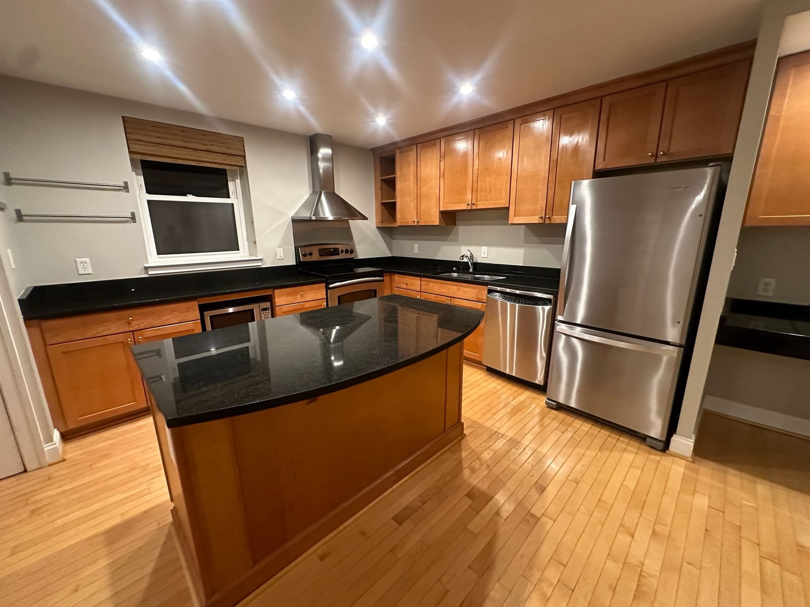 Kitchen with wood cabinets, stainless appliances and a black granite island
