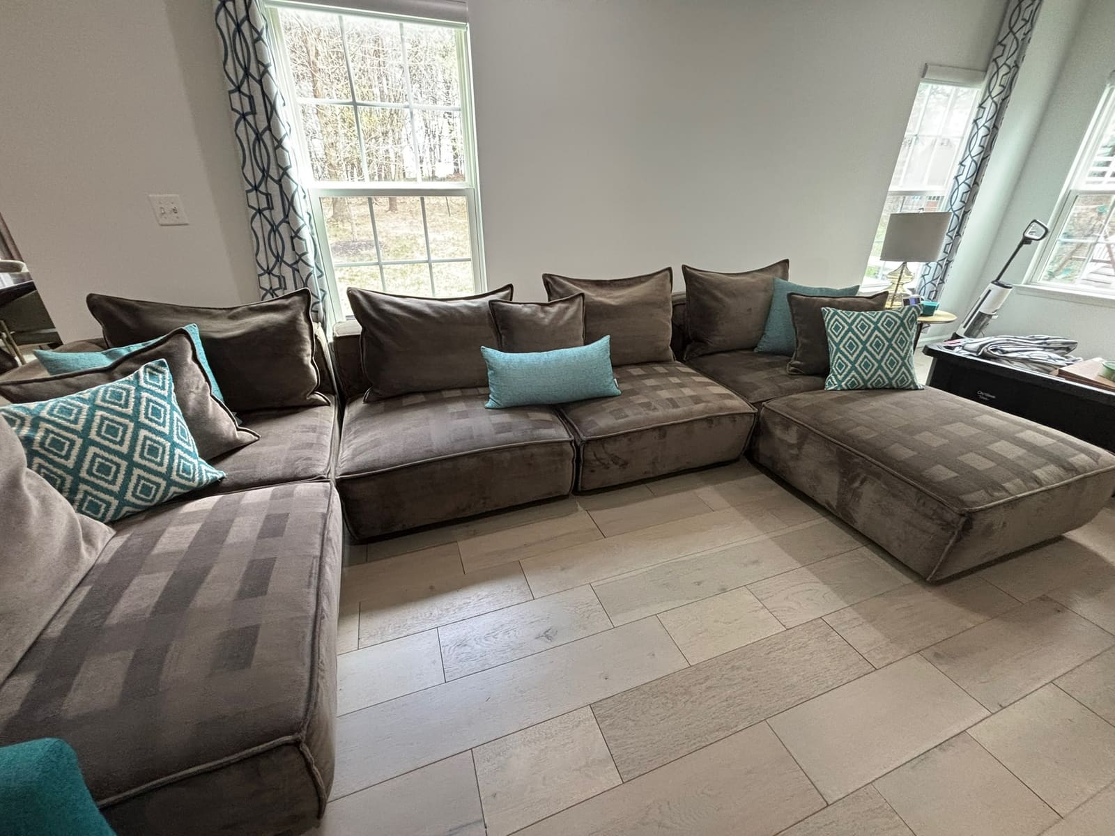 Living room with a large grey sectional and teal pillows